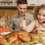 Family gathered around a dinner table enjoying a Thanksgiving meal with smiles and laughter.